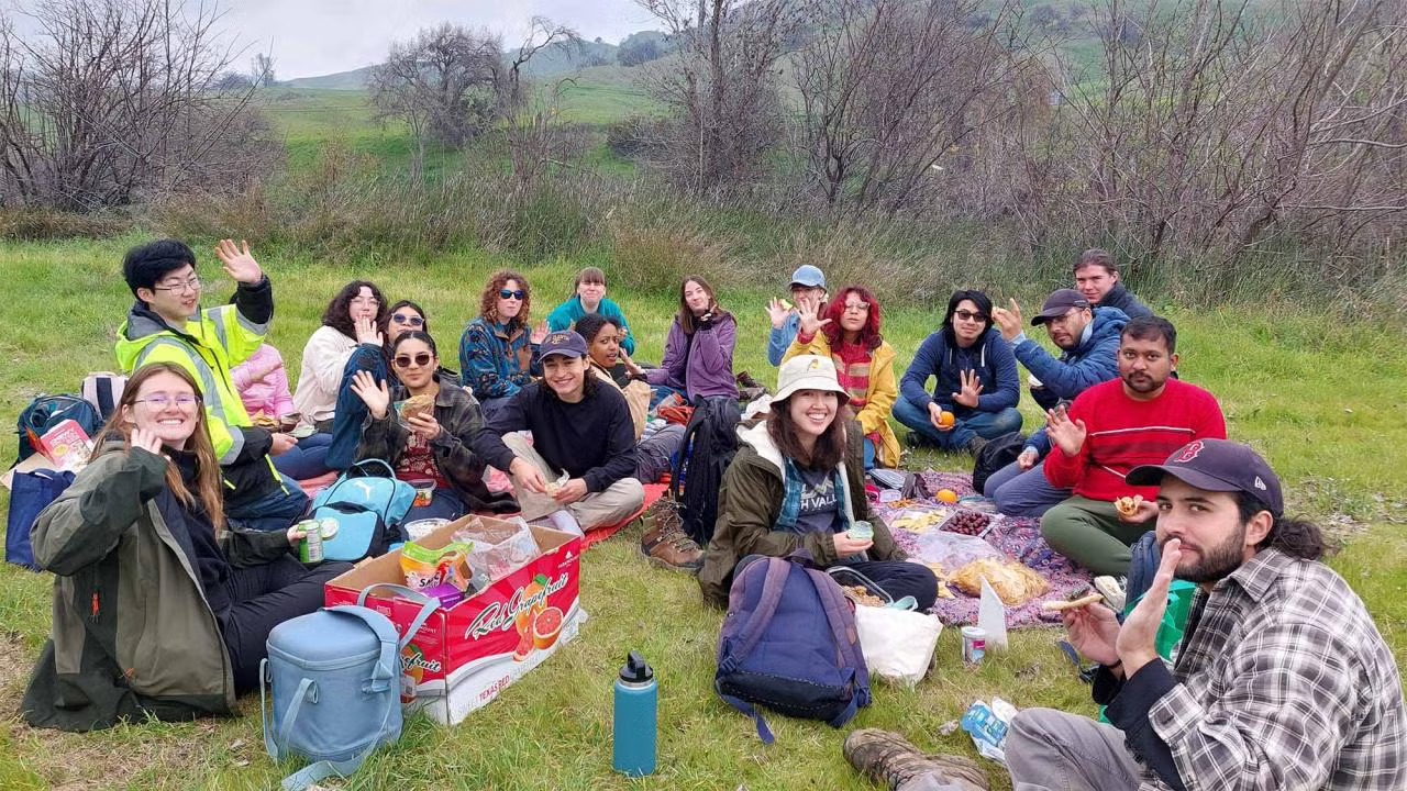 Group enjoying picnic on blankets in grassy hillside