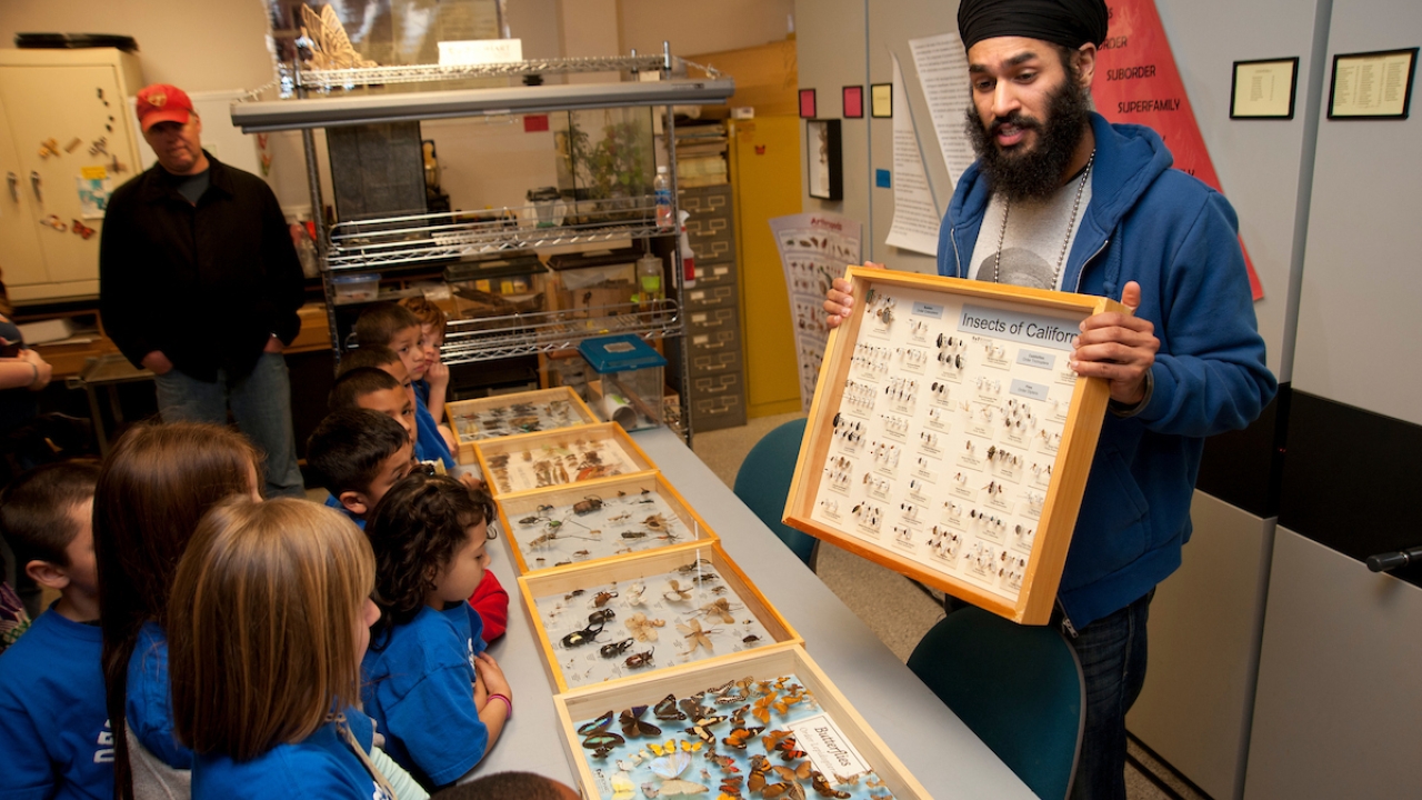 Photo of open house with a staff member showing students different exhibits