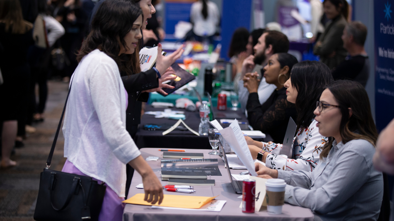 Photo of career fair attendees chatting with recruiters and employers