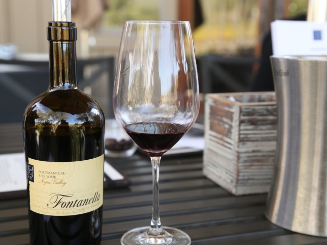 Bottle of red wine and filled wineglass on outdoor cafe table