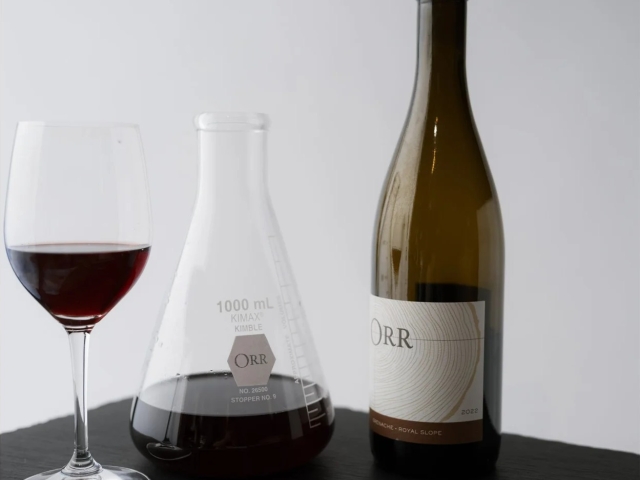 Decanter and glass of red wine with a bottle, corkscrew and notebook on a table