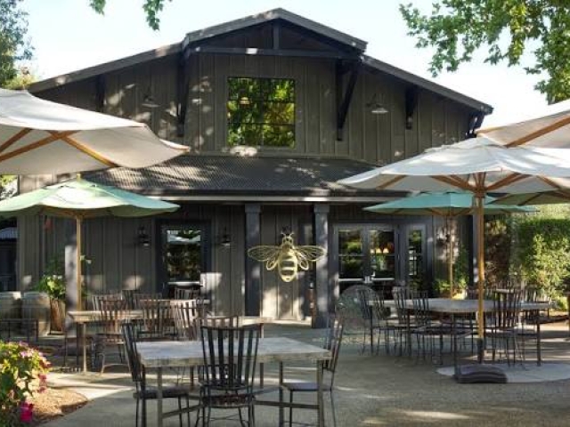 Outdoor cafe patio with tables and umbrellas before a dark wooden building