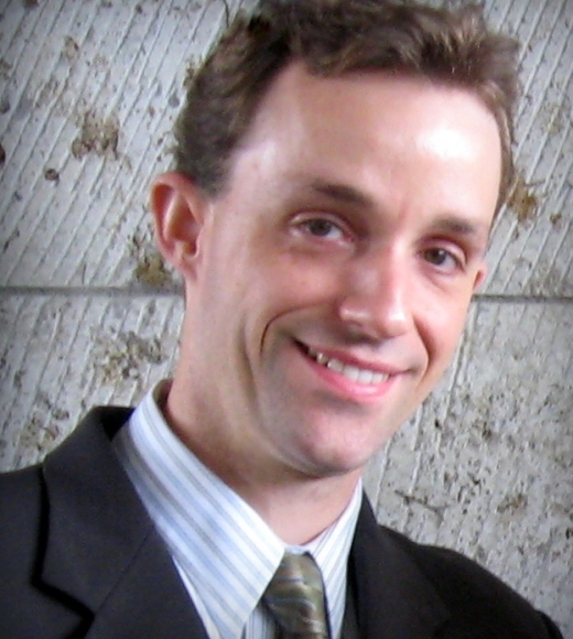 Smiling man in suit and tie against a textured concrete wall
