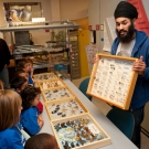 Photo of open house with a staff member showing students different exhibits