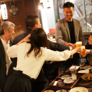 Photo of a group of people at a Japanese pub conducting a toast over some food. Paired with a banner that reads "UC Davis Japan Alumni Network"